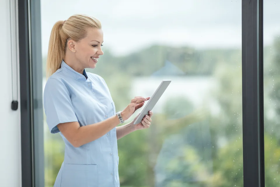 A nurse in scrubs reviewing patient information on a tablet